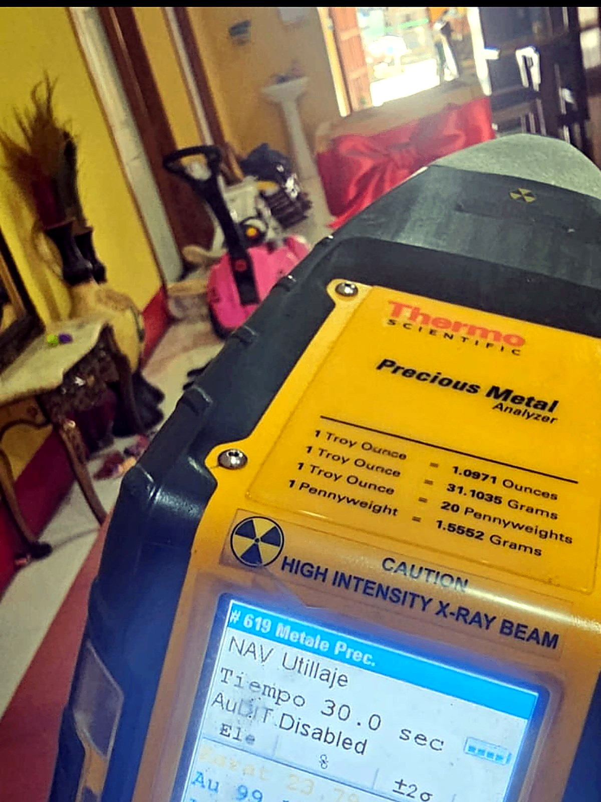 Yellow handheld X-ray fluorescence precious metal analyser displaying a gold purity reading of 99.14 percent