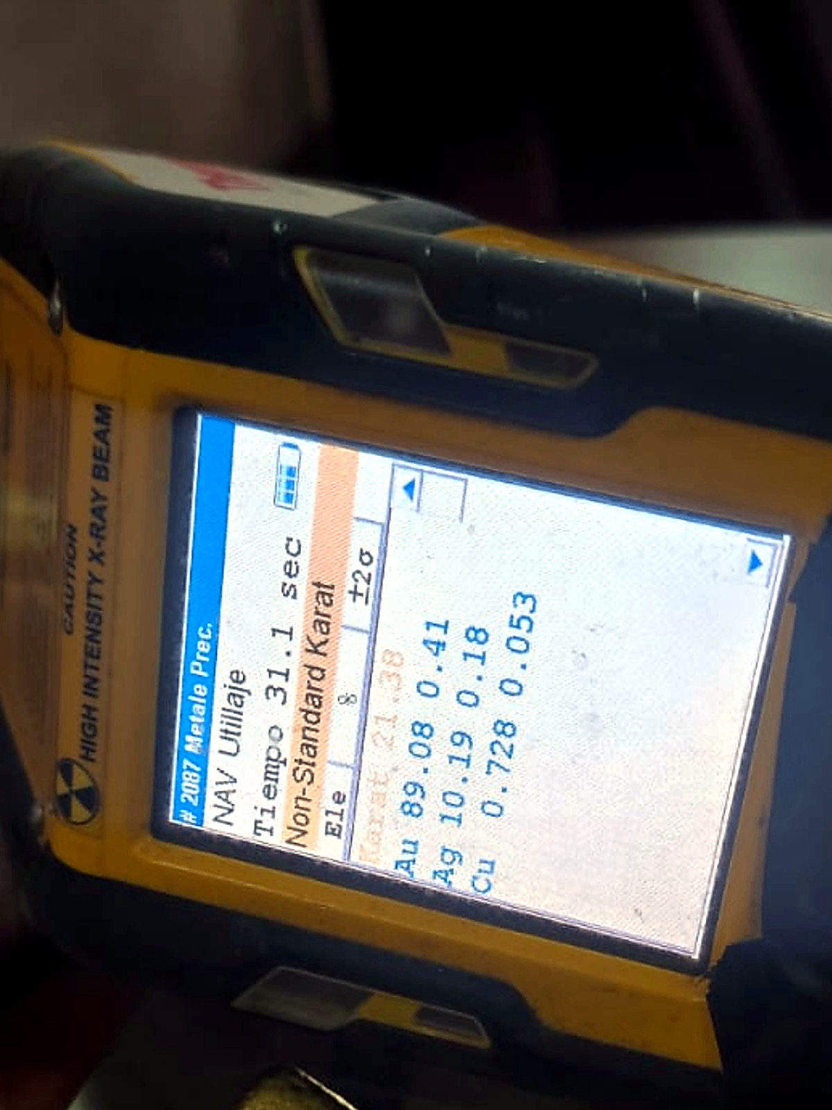 Small rectangular refined gold bar photographed beneath a handheld XRF analyser reporting 89 percent gold