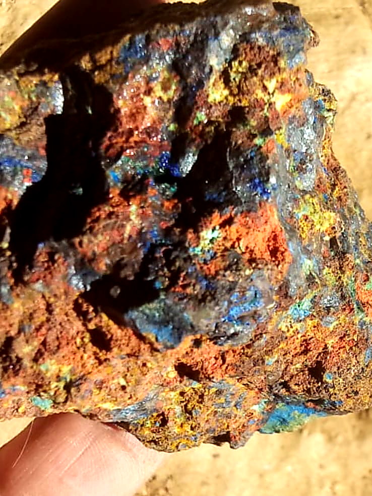 Hand-held rock specimen with vivid blue azurite, green malachite and orange iron oxide staining
