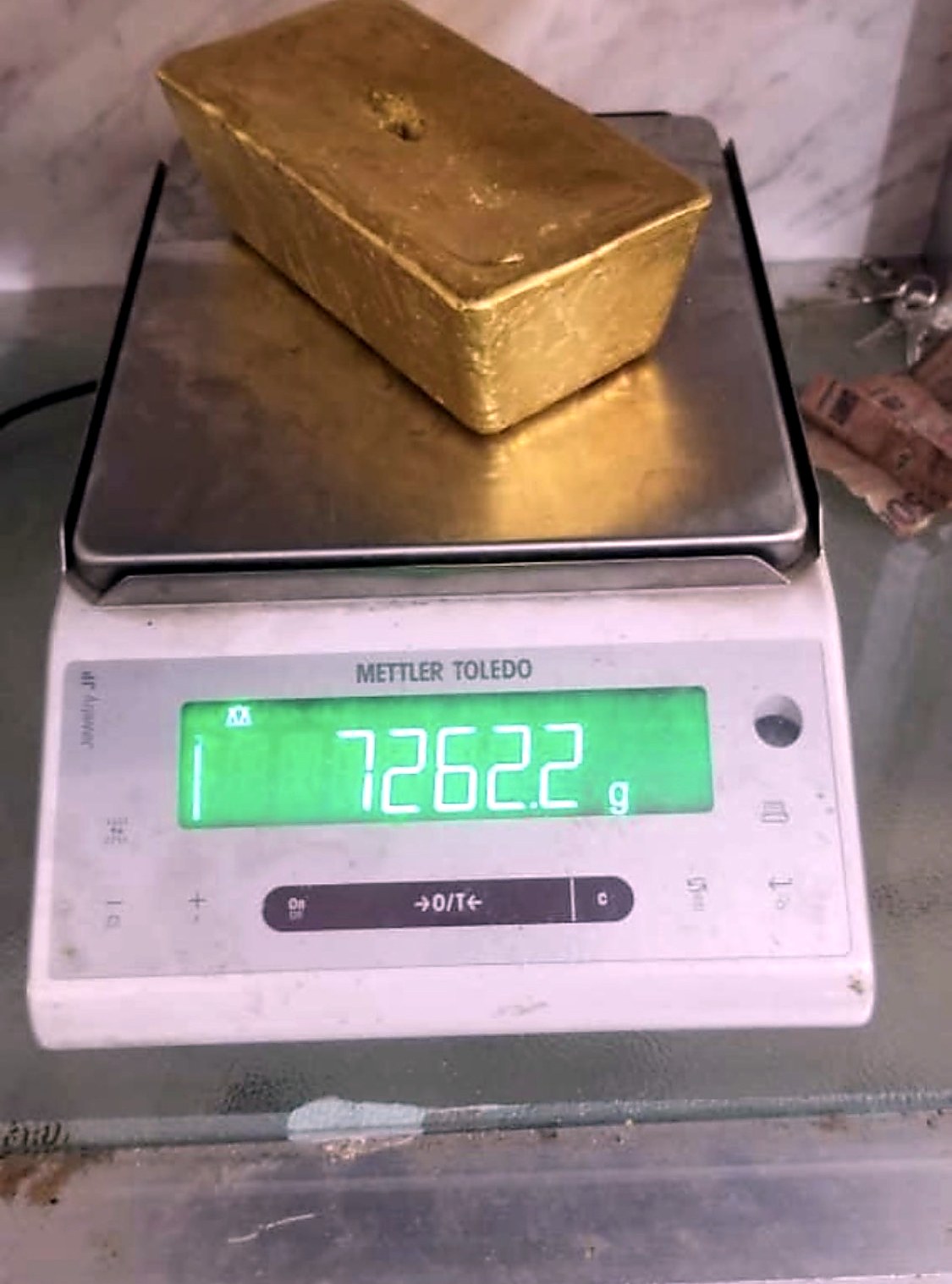 A large cast gold bar sitting on a Mettler Toledo precision scale reading 7262.2 grams