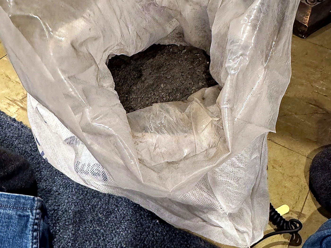 An open sack of grey mineral concentrate photographed during a second verification weighing