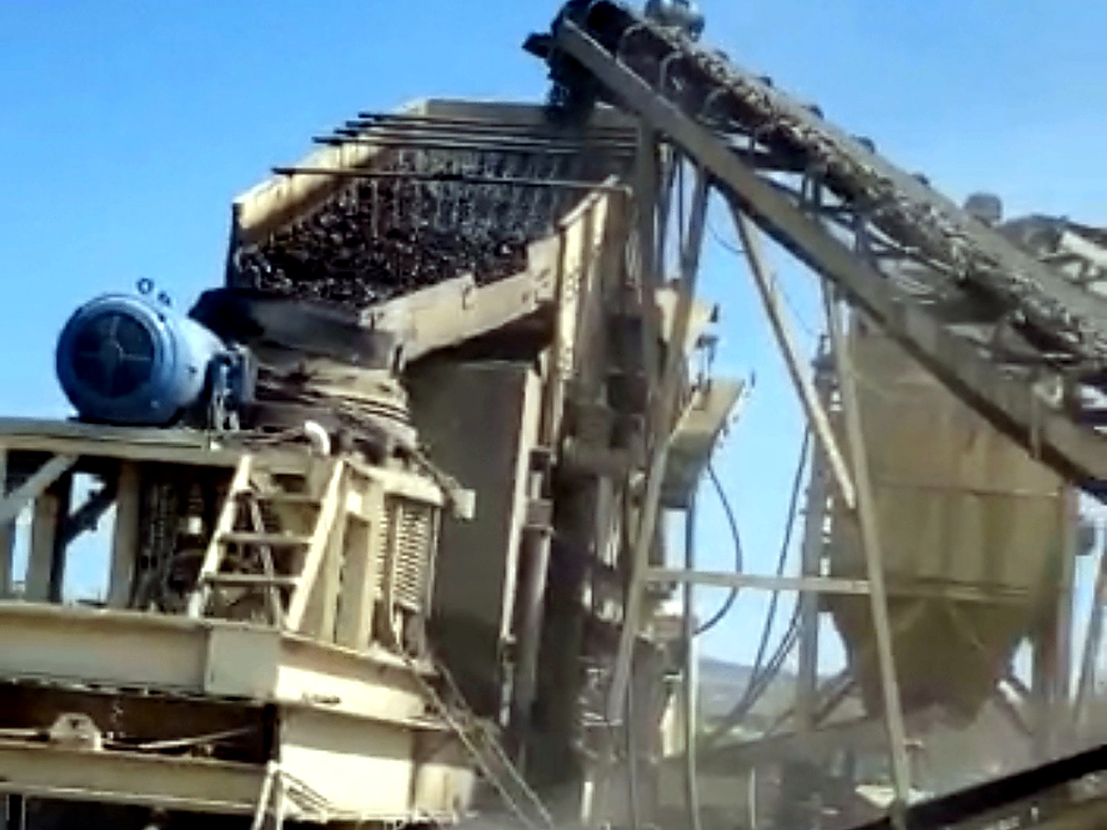 Industrial crushing and screening plant with multiple conveyors operating in a dusty outdoor yard